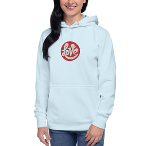 A woman is wearing a white hoodie featuring an embroidered, original "Love" design by Christian Clothing Brand - Loves Everywhere