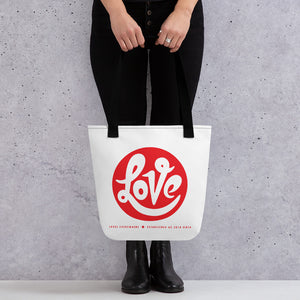 A woman is holding an original, printed tote bag "Love" design by Christian Clothing Brand, Loves Everywhere 