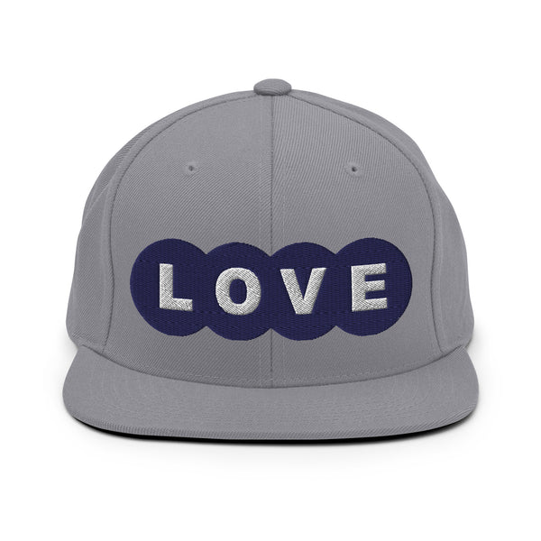 A silver snapback hat features an embroidered and original “Love” design by Christian Hat Company - Loves Everywhere