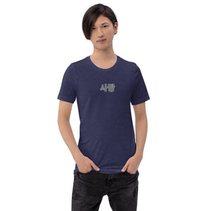 A man is wearing a heather navy blue Short Sleeve T-shirt featuring an embroidered, original “Love” design by Christian Shirt Company - Loves Everywhere