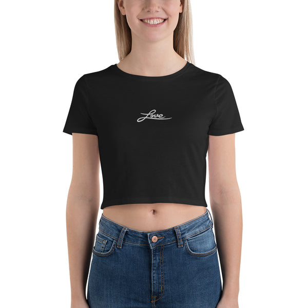 A woman is wearing a black Crop Top T Shirt featuring an embroidered original “Love” design by Christian Clothing Brand - Loves Everywhere