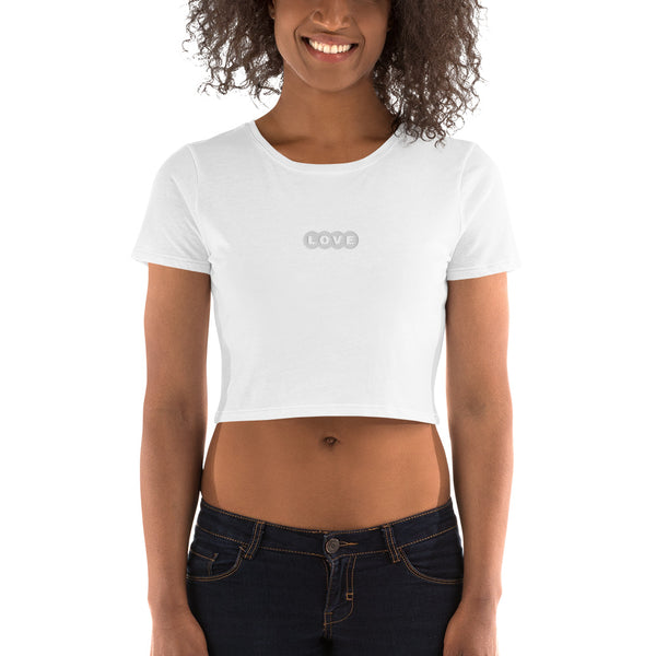 A woman is wearing a white Crop Top T Shirt featuring an embroidered original “Love” design by Christian Clothing Brand - Loves Everywhere