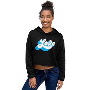 A woman is wearing a black crop hoodie featuring an original "Love" design print by Christian Clothing Brand - Loves Everywhere